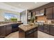 Kitchen featuring dark wood cabinetry, mosaic backsplash, stainless steel appliances, and a center island with granite countertops at 37654 N 102Nd Pl, Scottsdale, AZ 85262