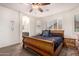 Bright bedroom with a doorway to the bathroom, a wooden bed frame, shutters on the windows, and a ceiling fan at 38062 W San Capistrano Ave, Maricopa, AZ 85138