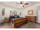 Comfortable bedroom showcasing a wooden bed frame, carpeted floor, shutters on the windows, and a ceiling fan at 38062 W San Capistrano Ave, Maricopa, AZ 85138