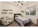 Comfortable bedroom with chair, decorative shelves, and window shutters, creating a serene space at 38062 W San Capistrano Ave, Maricopa, AZ 85138