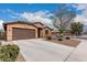 Single-story home with a two-car garage, desert landscaping and a long concrete driveway at 38062 W San Capistrano Ave, Maricopa, AZ 85138