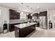 Modern kitchen with stainless steel appliances, mosaic backsplash, an island with granite countertops, and dark cabinets at 38062 W San Capistrano Ave, Maricopa, AZ 85138