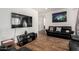 Living room with hardwood floors, a flat-screen TV, and a comfortable black leather sofa at 38062 W San Capistrano Ave, Maricopa, AZ 85138