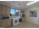 Bright laundry room with modern washer and dryer, cabinets for storage, and a window with views at 40262 N 107Th Pl, Scottsdale, AZ 85262