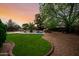 Expansive backyard featuring a lush green lawn, swimming pool with rock waterfall, and mature landscaping at 4662 W Fallen Leaf Ln, Glendale, AZ 85310