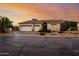 Beautiful single-story home featuring a three-car garage, desert landscaping, and a tile roof against a colorful sky at 4662 W Fallen Leaf Ln, Glendale, AZ 85310