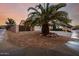 A desert landscape is seen from the street, featuring a well manicured yard and a towering palm tree at 4662 W Fallen Leaf Ln, Glendale, AZ 85310