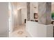 A view of a neutral hallway showcasing tiled floors and a view into an adjacent laundry room at 4662 W Fallen Leaf Ln, Glendale, AZ 85310