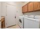 Functional laundry room with oak cabinets, countertop space, and modern appliances at 4662 W Fallen Leaf Ln, Glendale, AZ 85310