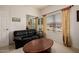 Comfortable living room with a leather sofa, window view, and mirrored closet doors at 4662 W Fallen Leaf Ln, Glendale, AZ 85310