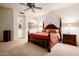 Bright main bedroom with a wooden four-poster bed, bedside tables, and neutral carpet at 4662 W Fallen Leaf Ln, Glendale, AZ 85310