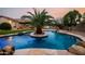 Backyard oasis with a uniquely designed pool featuring a rock waterfall and island palm tree at 4662 W Fallen Leaf Ln, Glendale, AZ 85310