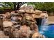 Beautiful rock waterfall cascading into the pool, creating a relaxing and natural oasis in the backyard at 4662 W Fallen Leaf Ln, Glendale, AZ 85310