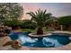 Stunning swimming pool featuring a central palm tree island, rock waterfall, and lush landscaping at 4662 W Fallen Leaf Ln, Glendale, AZ 85310