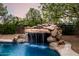 Detailed rock waterfall cascading into the refreshing backyard pool at 4662 W Fallen Leaf Ln, Glendale, AZ 85310