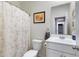 Well-lit bathroom with vanity, toilet, framed art, and decorative shower curtain at 47737 W Coe St, Maricopa, AZ 85139