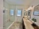 Bright bathroom featuring a glass shower, neutral tile flooring, and double sink vanity with framed mirrors at 5146 W Echo Ln, Glendale, AZ 85302