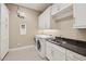 Well-lit laundry room with white cabinets, gray countertop, stainless sink, and front-loading washer and dryer at 5411 E Duane Ln, Cave Creek, AZ 85331