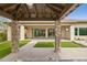 Outdoor kitchen's stone pillars leading to a covered patio with a built-in grill, artificial turf, and desert landscaping at 5411 E Duane Ln, Cave Creek, AZ 85331