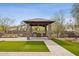 Outdoor kitchen area with built-in grill, stone pillars, and a covered roof, surrounded by landscaping at 5411 E Duane Ln, Cave Creek, AZ 85331