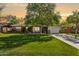 Charming single-story brick home with lush green lawn and mature tree, featuring a cozy front porch at 5529 N 19Th St, Phoenix, AZ 85016