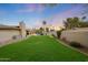 Large backyard featuring lush green lawn, covered patio, fenced perimeter, and a sparkling pool at 6309 E Crocus Dr, Scottsdale, AZ 85254