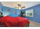 A colorful bedroom with blue walls, a ceiling fan, and a window with white shutters at 6309 E Crocus Dr, Scottsdale, AZ 85254