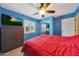 Well-lit bedroom with blue walls, a ceiling fan, and a window with white shutters at 6309 E Crocus Dr, Scottsdale, AZ 85254