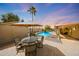 Outdoor patio area featuring a dining table, outdoor lighting, a BBQ and a serene pool view at 6309 E Crocus Dr, Scottsdale, AZ 85254