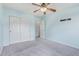 This neutral carpeted bedroom features a ceiling fan, closet, and entry door at 900 W Broadway Ave # 66, Apache Junction, AZ 85120