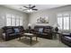 Relaxing living room featuring leather sofas, a ceiling fan, and bright shuttered windows at 9149 E Auburn St, Mesa, AZ 85207