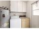 Cozy laundry room featuring a washer, dryer, water heater, storage cabinets and a door at 9614 W Pleasant Valley Rd, Sun City, AZ 85351