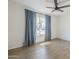 Bright bedroom with wood-style flooring, a ceiling fan, and a window with blue curtains at 11026 W Bluefield Ct, Sun City, AZ 85351