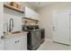 Functional laundry room with modern appliances, cabinetry, wood shelves, and a utility sink at 11416 E Palomino Rd, Scottsdale, AZ 85259