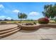 Multi-level back patio featuring stone steps, a serene waterfall, and lush greenery at 15751 W Linksview Dr, Surprise, AZ 85374