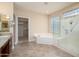 Bright bathroom featuring a soaking tub, glass enclosed shower, and walk-in closet at 15751 W Linksview Dr, Surprise, AZ 85374