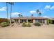 Rear exterior view featuring a covered patio, desert landscaping, and solar panels on the roof at 15751 W Linksview Dr, Surprise, AZ 85374