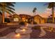 Elegant home featuring lit entryway steps, a stone facade, and lush desert landscaping at twilight at 15751 W Linksview Dr, Surprise, AZ 85374