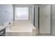 Bright bathroom featuring a soaking tub, glass-enclosed shower, and a window for natural light at 16167 W Cottonwood St, Surprise, AZ 85374