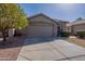 Inviting home exterior featuring a spacious driveway, desert landscaping and a mature orange tree at 16167 W Cottonwood St, Surprise, AZ 85374