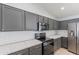 This kitchen includes gray cabinets, stainless steel appliances, white backsplash, and a stainless steel microwave at 16167 W Cottonwood St, Surprise, AZ 85374