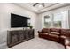 Spacious living room with a leather sofa, media center, tray ceiling, and natural light at 23145 E Stonecrest Dr, Queen Creek, AZ 85142