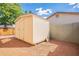 Backyard storage shed with a wooden door, situated on a gravel base with ample space around it at 2317 E Concorda Dr, Tempe, AZ 85282
