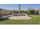 Backyard concrete patio with an integrated bench surrounded by green lawn at 4243 S Hackberry Trl, Gold Canyon, AZ 85118