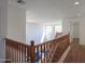 Bright hallway with wood floors and a wooden railing overlooking the living room at 44115 W Palmen Dr, Maricopa, AZ 85138