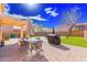 Backyard patio features an outdoor dining set, grill, putting green, and desert landscaping at 44165 W Kramer Ln, Maricopa, AZ 85138