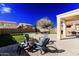 Inviting backyard with a fire pit, covered patio, lush green turf, and serene outdoor seating for relaxation at 44165 W Kramer Ln, Maricopa, AZ 85138