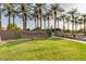 Community entrance sign with lush landscaping and tall palm trees creating a welcoming atmosphere at 44165 W Kramer Ln, Maricopa, AZ 85138