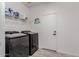 This laundry room has black washer and dryer, shelving, and grey wood-look flooring at 44165 W Kramer Ln, Maricopa, AZ 85138