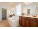 Bright bathroom with a soaking tub, dual vanity with dark cabinets, and a large window for natural light at 5721 W Molly Ln, Phoenix, AZ 85083